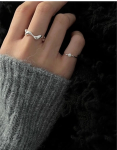 Close-up of minimalist S925 silver wave ring and pearl finger ring on model hand