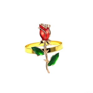 Detailed view of gold metal napkin ring featuring red enamel rose with crystal accents