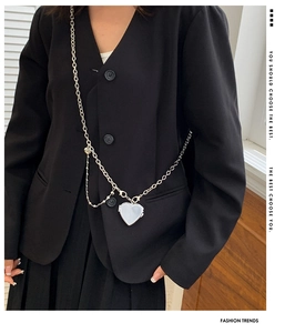 Silver heart locket necklace with layered chain on black blazer jacket closeup