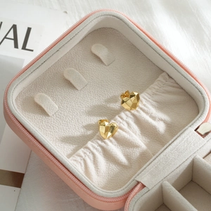 Macro shot of geometric heart stud earrings in gold finish inside a pink jewelry box