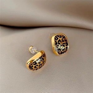 French style gold-plated leopard print stud earrings on champagne silk fabric background