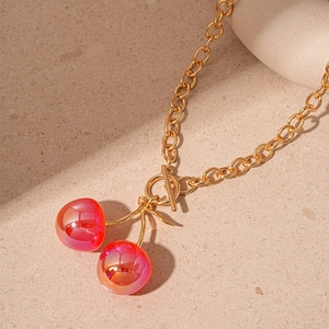 Detail of gold chain necklace featuring red resin cherry pendants and elegant OT clasp
