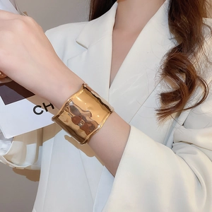 Close-up of wide gold-plated cuff bracelet featuring a unique irregular lava texture