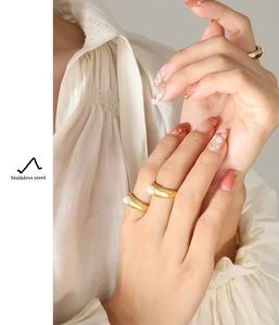 Detailed view of wide gold stainless steel rings with freshwater pearl on a model finger