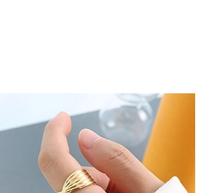 Macro shot of a gold ring with textured wavy patterns worn on a finger with clear focus