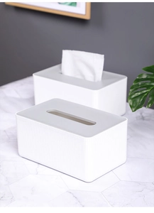 Detail of white rectangular tissue box with grey lid and vertical stripes on marble desk
