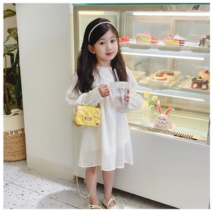 Close-up of a little girl wearing a yellow quilted mini shoulder bag with a white dress