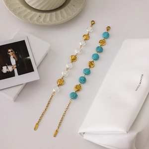 Vintage stainless steel bracelets with glass pearls and turquoise beads on white ceramic