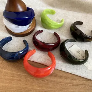 Minimalist thick acrylic cuff bracelet in vibrant colors shown on a rustic display
