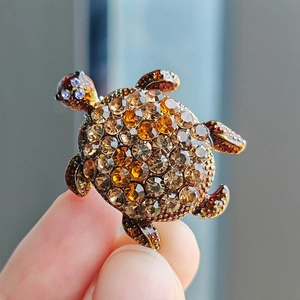 Close-up of turtle brooch featuring amber rhinestones on a vintage metal base