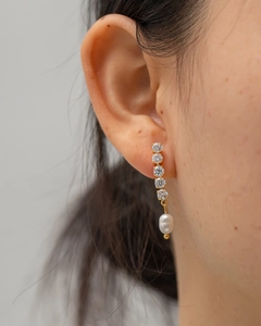 Macro shot of long drop earrings with zircon stones and a white freshwater pearl