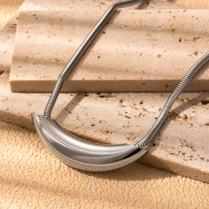 Minimalist silver stainless steel snake chain necklace with curved metal pendant on stone