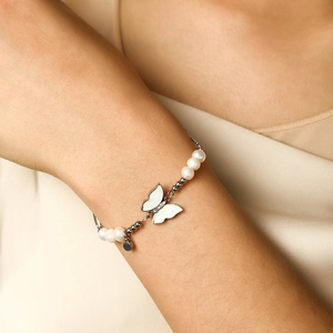Detail of silver butterfly and pearl chain bracelet worn on a female wrist