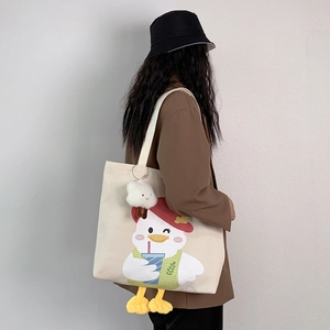Detail of canvas tote bag with cartoon duck print and white cloud plush pendant charm