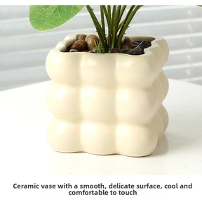 Detail of creamy white ceramic pot with cloud-like texture and decorative dark pebbles