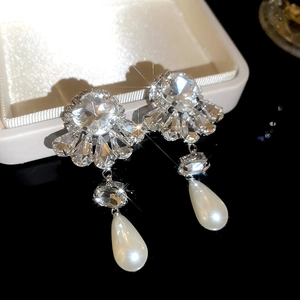 Close-up of sparkling rhinestone flower earrings with teardrop pearl pendants