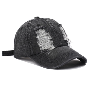 Close-up of distressed ripped details on a black washed denim baseball cap for street style