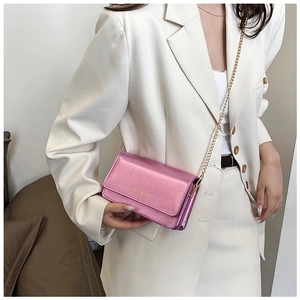 Detail of metallic pink crossbody bag with gold chain strap on white suit outfit