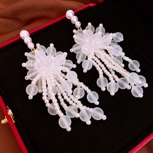 Dettaglio degli orecchini a fiore in acrilico con nappe di perle in una confezione regalo