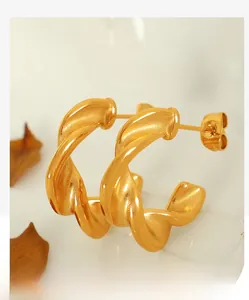Macro shot of twisted gold C-shaped earrings with a polished Moebius design