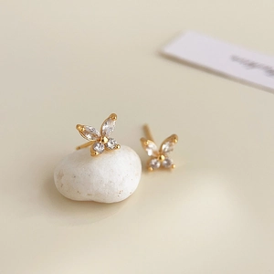 Macro detail of 18K gold-plated butterfly stud earrings with sparkling cubic zirconia