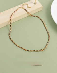 Gros plan du collier en œil de tigre avec pendentif soleil en acier inoxydable
