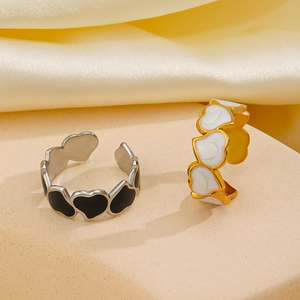 Adjustable stainless steel heart enamel rings in black and white shown on silk background