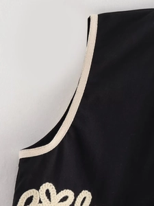 Gros plan sur tissu noir avec bordure tressée crème et détails de broderie fine