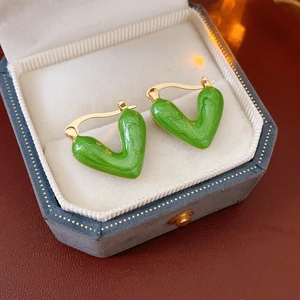 Close-up of vintage green enamel V-shaped hoop earrings in a luxury velvet jewelry box