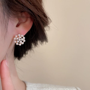 Detail view of round pearl cluster earrings in gold base worn on a female ear model