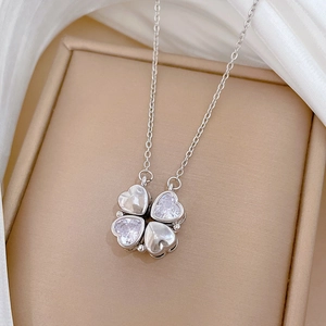 Collana a quadrifoglio argento con cristalli su scatola beige e sfondo in seta bianca