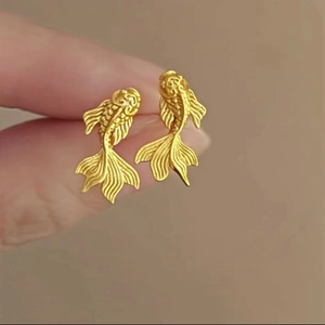 Detailed macro view of gold-plated goldfish stud earrings with intricate scales and fins