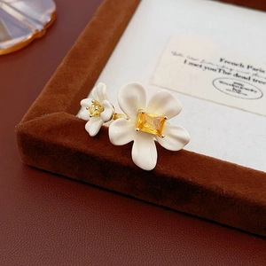 Detailed macro view of white enamel flower ring with yellow gemstone and gold finish