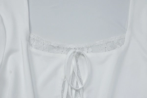 Close-up of square neckline with delicate lace trim and drawstring tie on white top