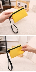 Vue détaillée d'un porte-monnaie jaune vif en polyester avec une dragonne noire tressée