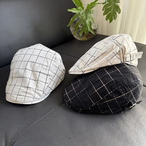 Detail of plaid linen flat caps in white and black with adjustable metal side buckles