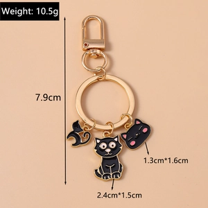 Detailed view of black cat charms on a golden keychain with precise size measurements