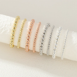 Close-up of elastic bead rings in gold, rose gold, and silver finishes with polished textures