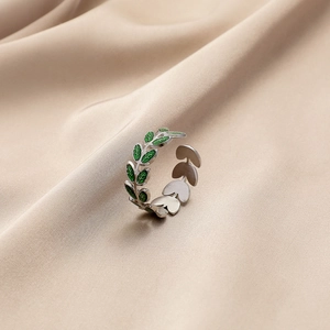 Detail of silver olive branch ring with green enamel leaves on silk fabric