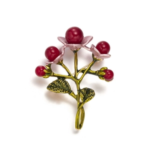 Macro shot of vintage berry brooch with red beads and green enamel leaves details