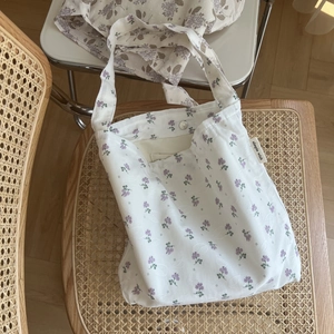 Detail of floral tote bag with metallic snap closure and textured cotton fabric surface