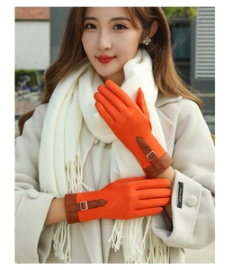 Detail of orange suede gloves for women featuring touch screen design and a buckle