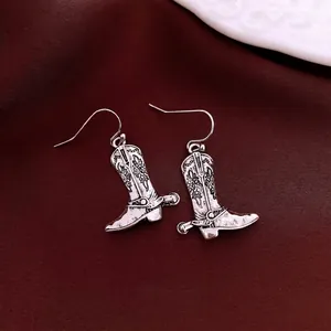 Vintage silver cowboy boot earrings with floral engraving and spurs on red velvet