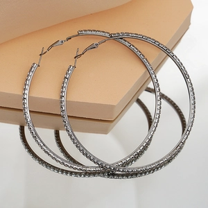 Detailed view of gun black hoop earrings with white rhinestones on aesthetic displays