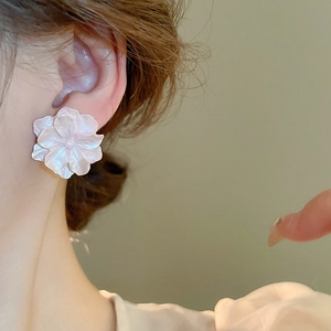 Detailed view of camellia flower earring featuring pearl luster on model's ear