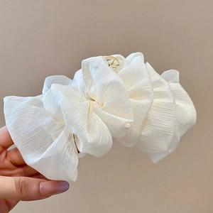 Close-up of white ruffled mesh hair claw clip with iridescent fabric and gold metal grip