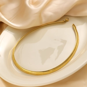 Close-up of flat 18k gold plated snake chain necklace on silk and ceramic display