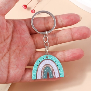 Detail view of a boho acrylic rainbow keychain with mint and purple spots held in hand