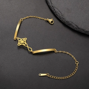 Detail of a gold titanium steel bracelet featuring a hollow flower charm on a black base