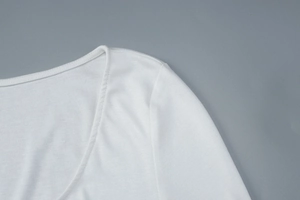 Détail de la texture en maille côtelée blanche et du décolleté en V d'une robe ajustée